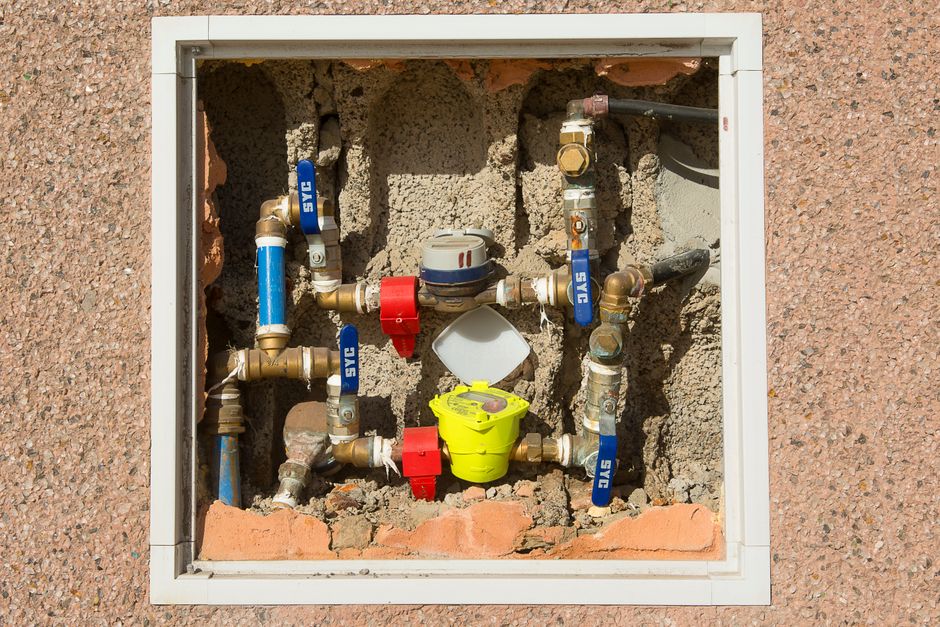 Close-up of a complex water meter and valve assembly embedded in concrete — municipal backflow device context in Jurupa Valley.
