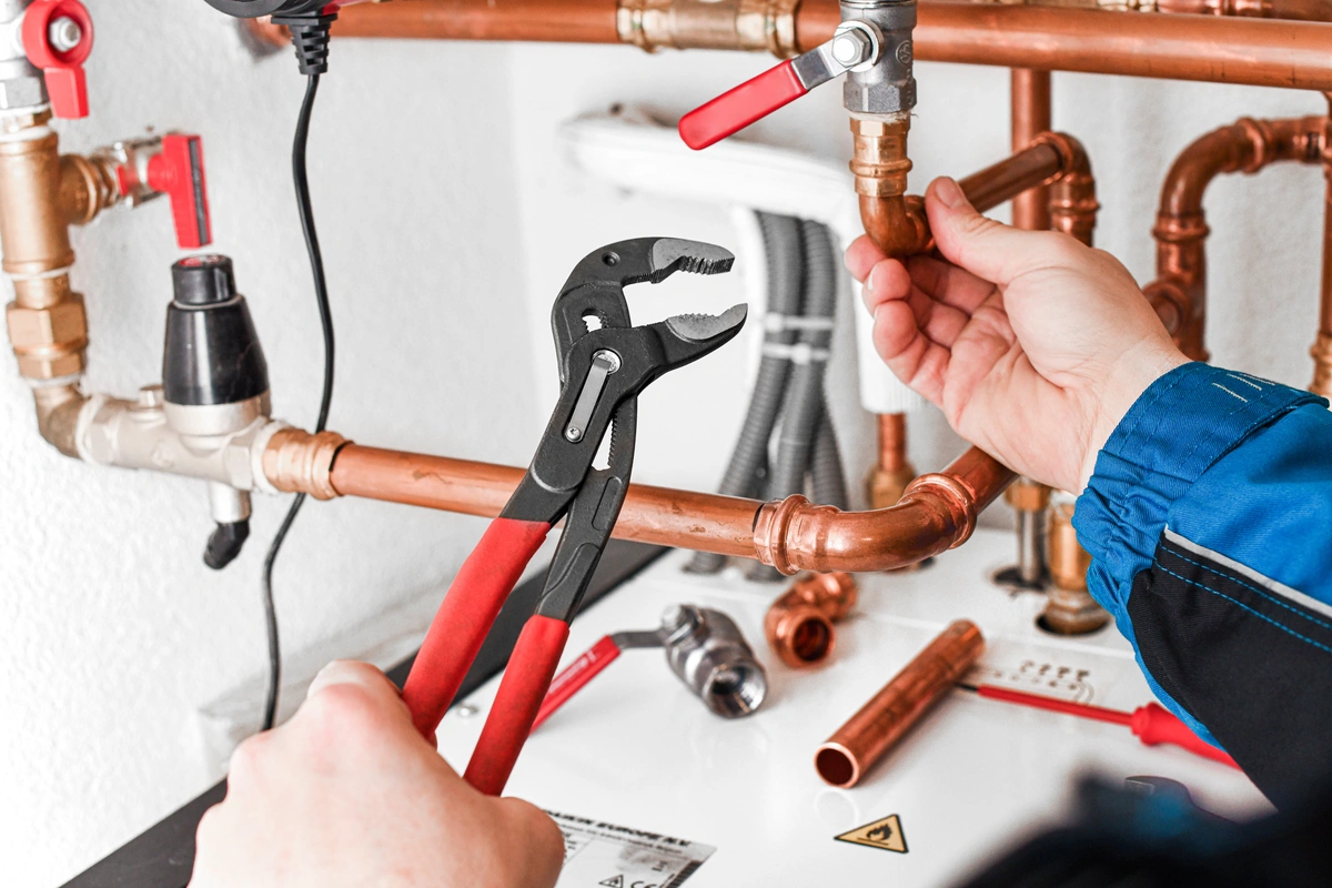 Plumber repairing copper pipes with pliers during pipe repair and repiping service in Jurupa Valley, CA