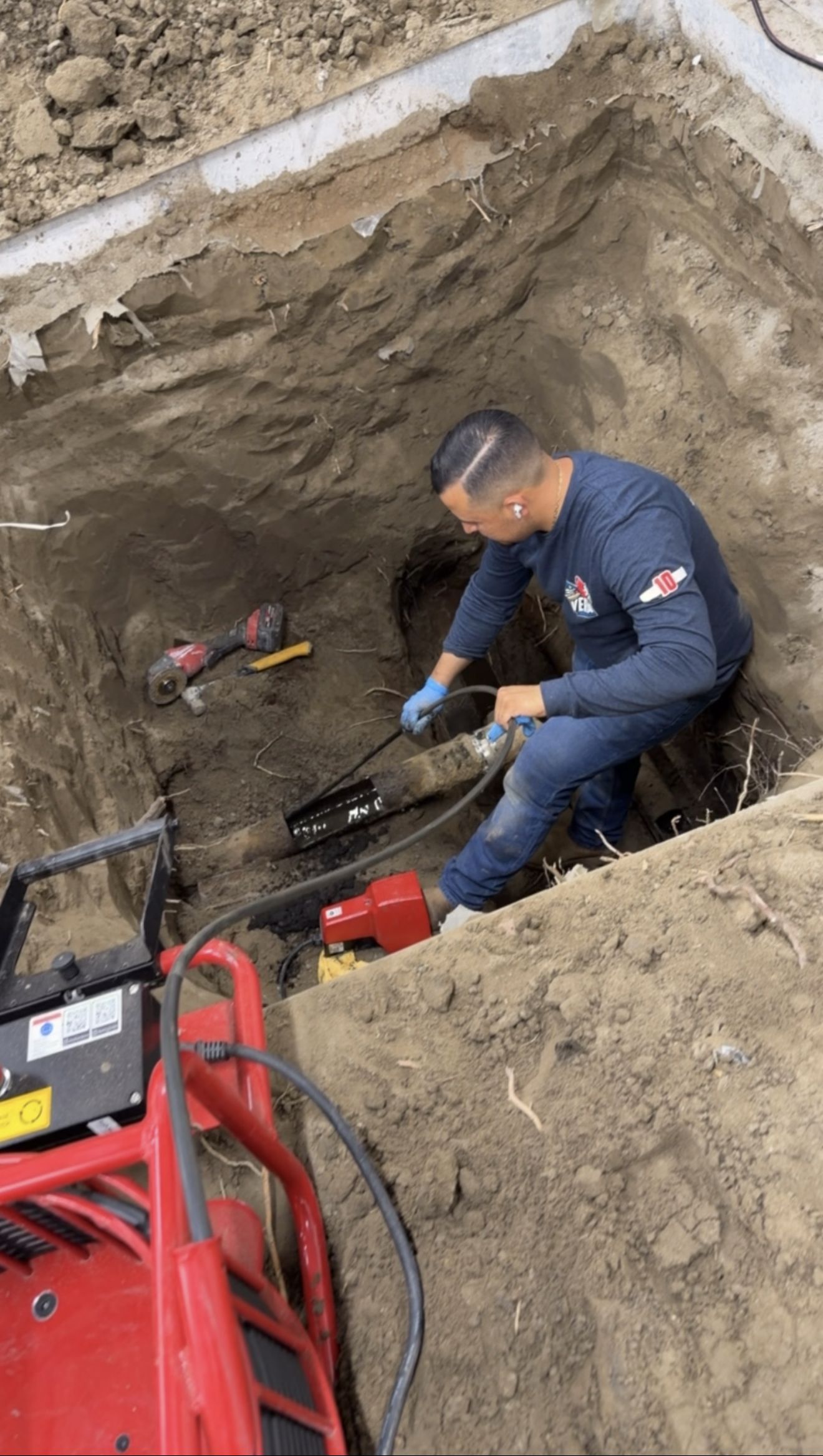 Plumber repairing a sewer line in an excavated trench in Jurupa Valley, CA